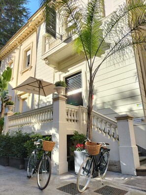 A building with a balcony, a bicycle, and a planter with flowers.