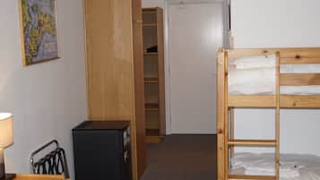Un dormitorio con una cama litera, un escritorio, una silla, una lámpara y un armario.
