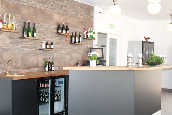 A bar area with shelves of bottles, a refrigerator, and a sink.