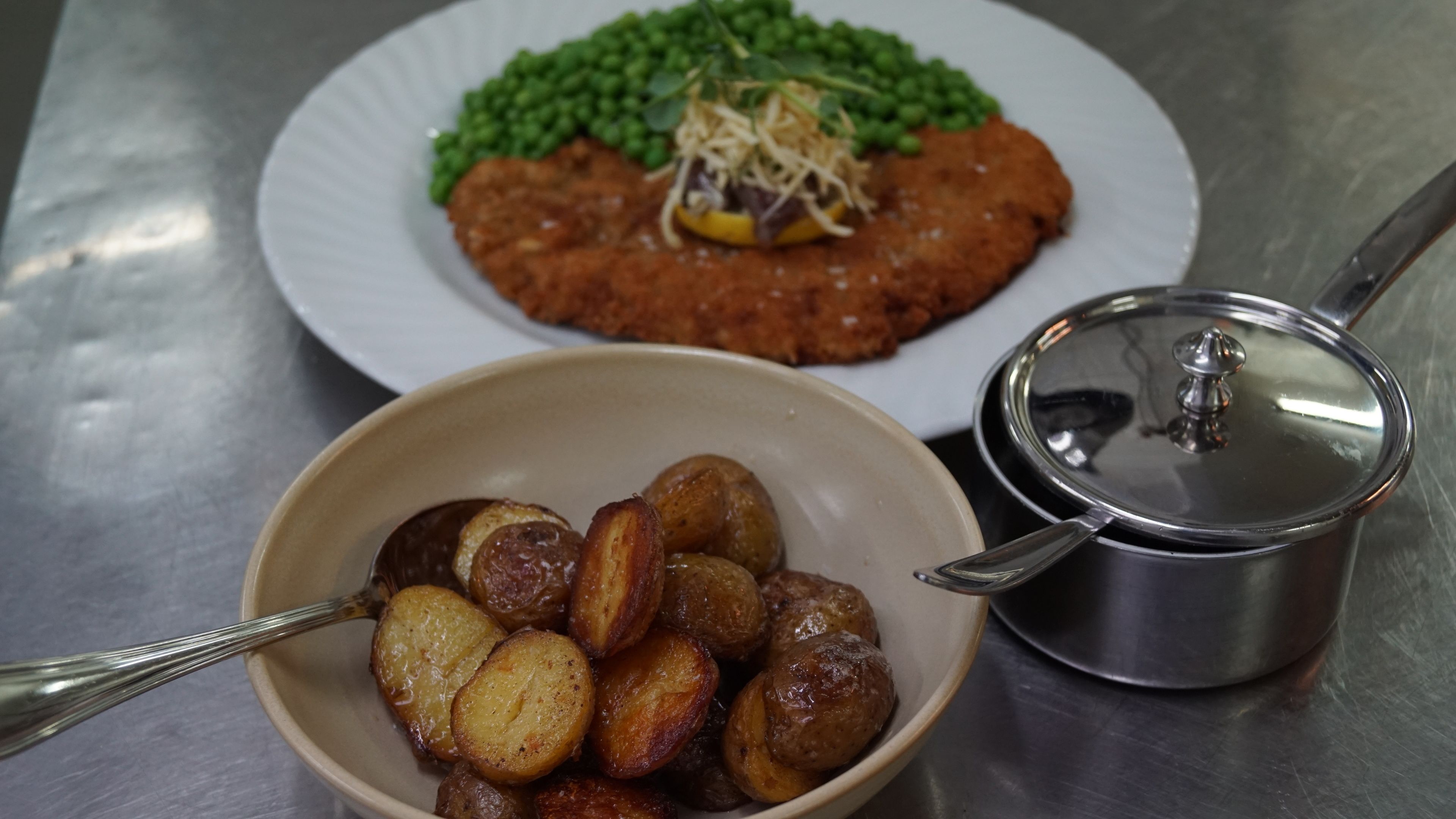 Un plato con un guiso de carne, guisantes y una guarnición de patatas asadas.