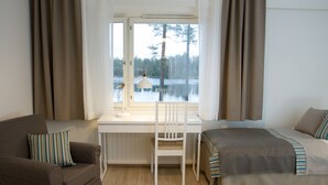 Una habitación con escritorio, silla, cama y ventana con vistas al lago.