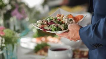 A person serving a salad at a buffet.