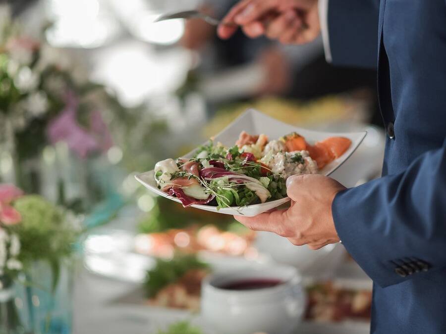 Una persona sirve ensalada en un bufé.