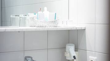 Un baño con un lavabo blanco, un espejo y una repisa con artículos de tocador.