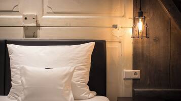 Een bed met witte kussens, een houten hoofdbord en een wandlamp.