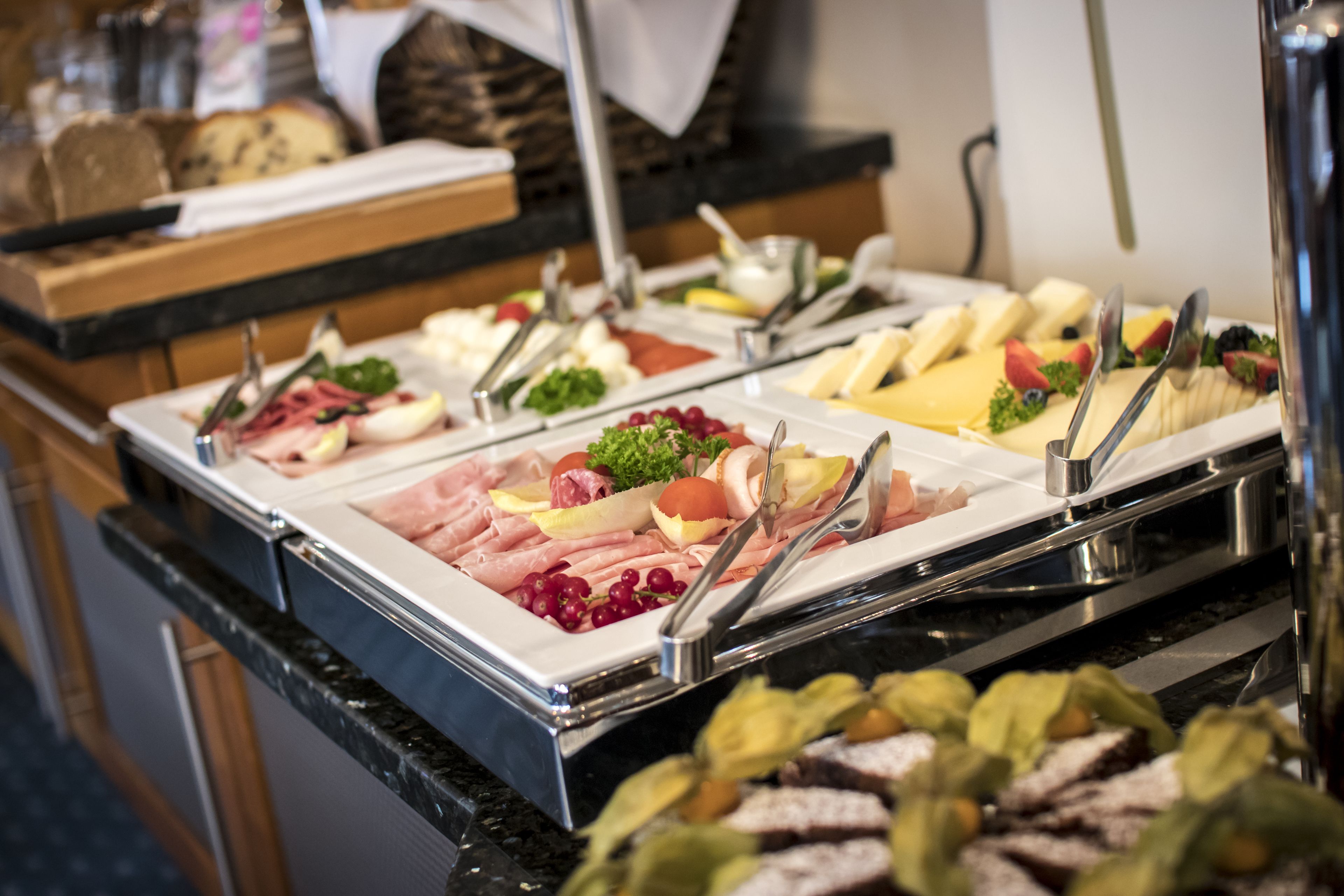 A buffet with various food items including meats, cheeses, and fruits.