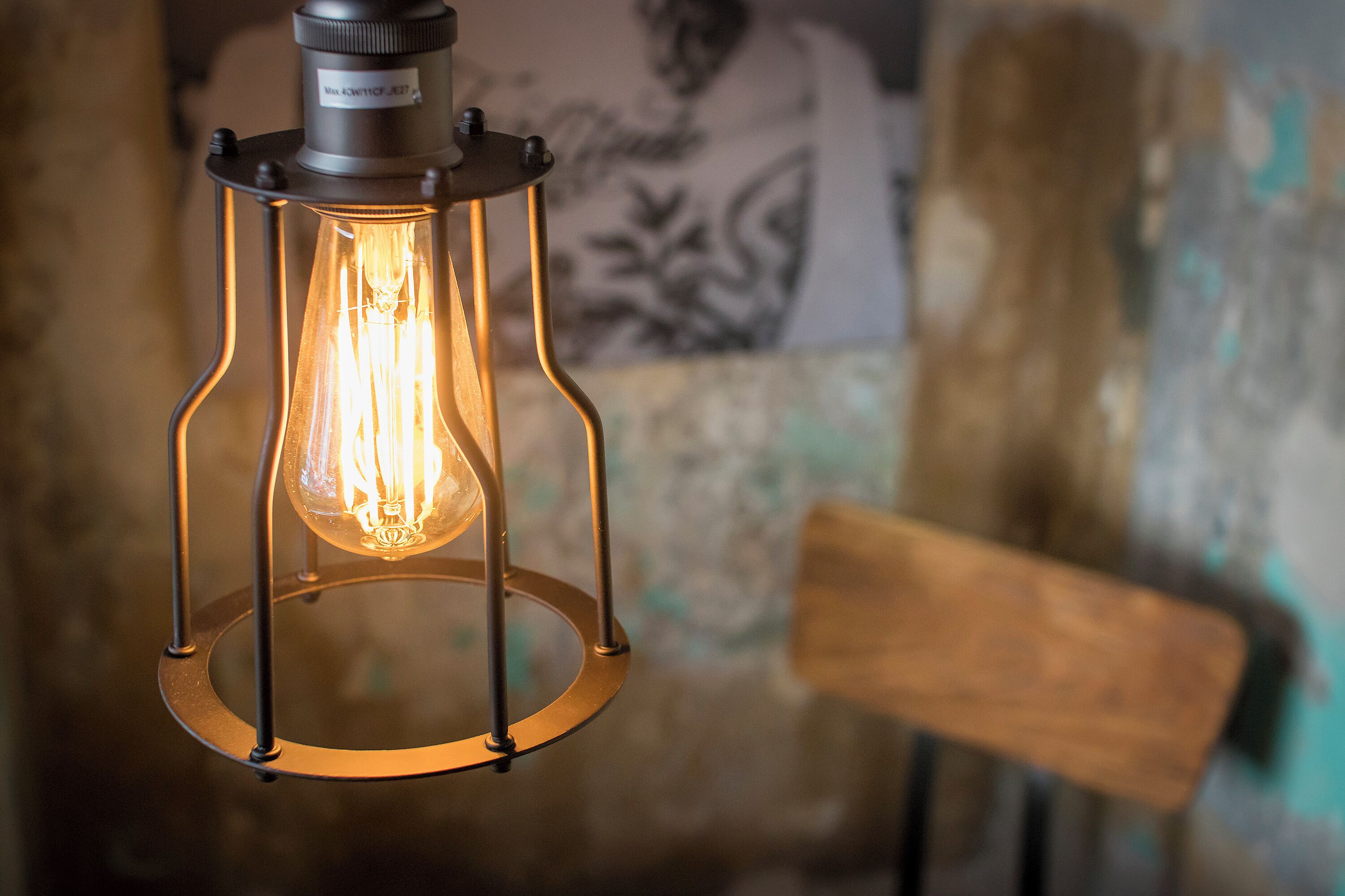 A close-up of a vintage-style hanging light fixture with a visible filament bulb.
