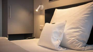 A neatly made bed with white linens and pillows, a bedside lamp, and a modern headboard.