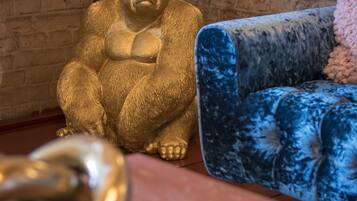 A room with a brick wall, a blue velvet sofa, and a golden statue.