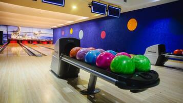 Une salle de bowling dotée de plusieurs pistes, d’un système de retour automatique des boules et d’un mur décoré de motifs circulaires colorés.