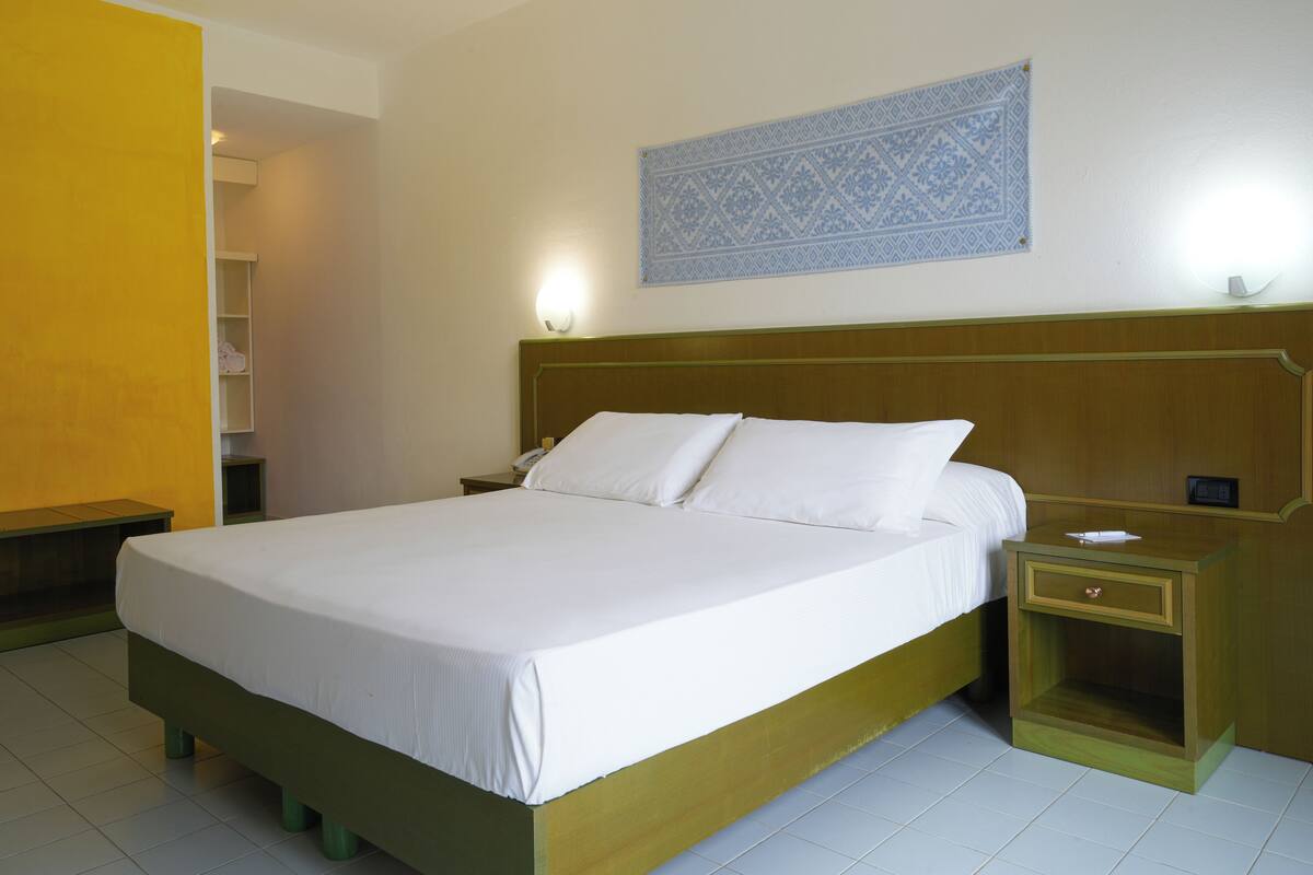 Een net opgemaakt bed met witte lakens in een hotelkamer.