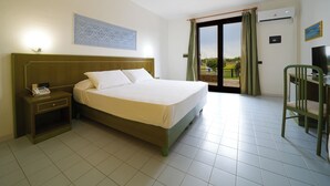 Une chambre d’hôtel avec un lit, un bureau et une chaise, un téléphone et une vue sur l’extérieur, visible depuis la porte.