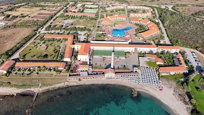 Vue aérienne d’une station balnéaire dotée d’une piscine, de courts de tennis et d’un port de plaisance.