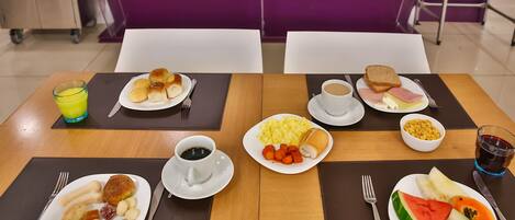 A breakfast setting with various food items and drinks on a table.