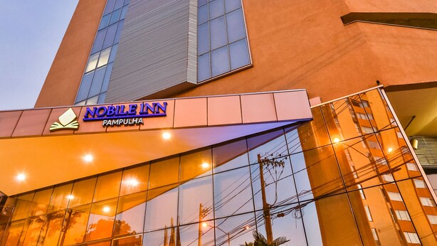 A modern building with a prominent 'Noble Inn' sign, large glass windows, and a reflective facade. - Nobile Inn Pampulha (Belo Horizonte)