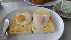 A plate with two pieces of toast topped with fried eggs.