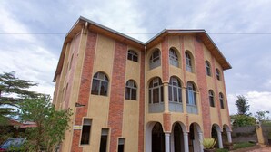 A large, multi-story building with a brick facade and multiple windows. - Sinai Suites Hotel (Kigali)