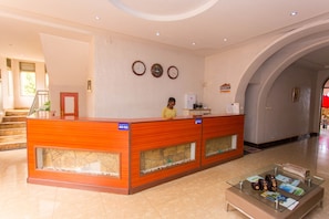 A reception area with a wooden reception desk, a receptionist, and a glass display case with brochures.