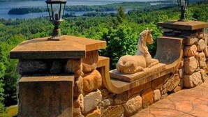 A stone bench with a horse sculpture and two lanterns, overlooking a scenic landscape with mountains and a lake. - HIGHLANDS CASTLE overlooking Lake George.. plus 2 other Castles! (Bolton Landing)