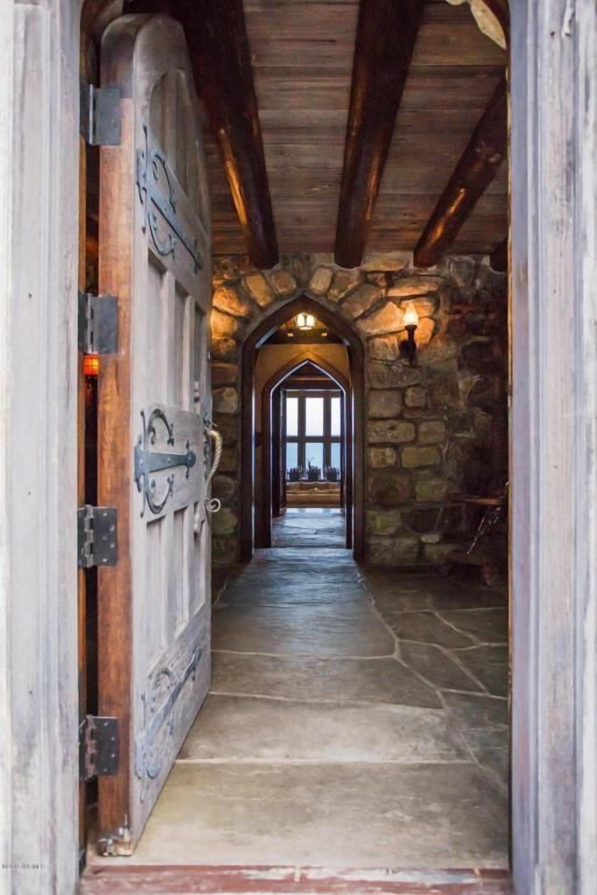 A stone-walled hallway with a wooden door and a stone floor.