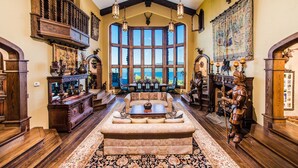 A spacious room with a large window, wooden furniture, and a fireplace. - HIGHLANDS CASTLE overlooking Lake George.. plus 2 other Castles! (Bolton Landing)