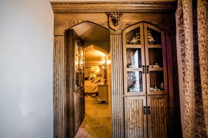 A wooden hallway with a carved archway leading to a bedroom.