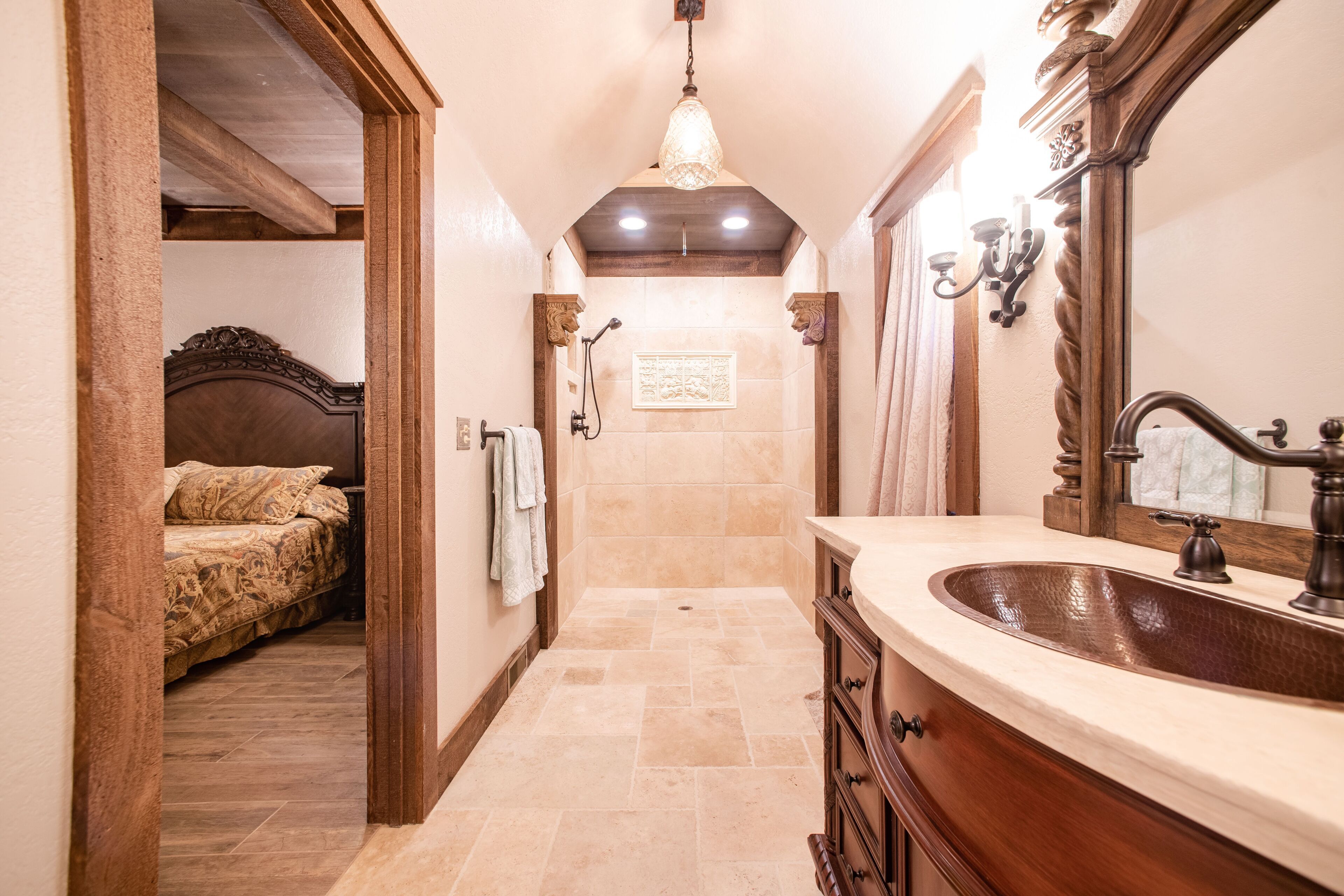 A narrow hallway leading to a bathroom with a large mirror, a sink, and a shower.