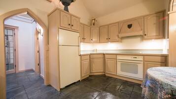 A kitchen with light wooden cabinets, a refrigerator, an oven, and a sink.