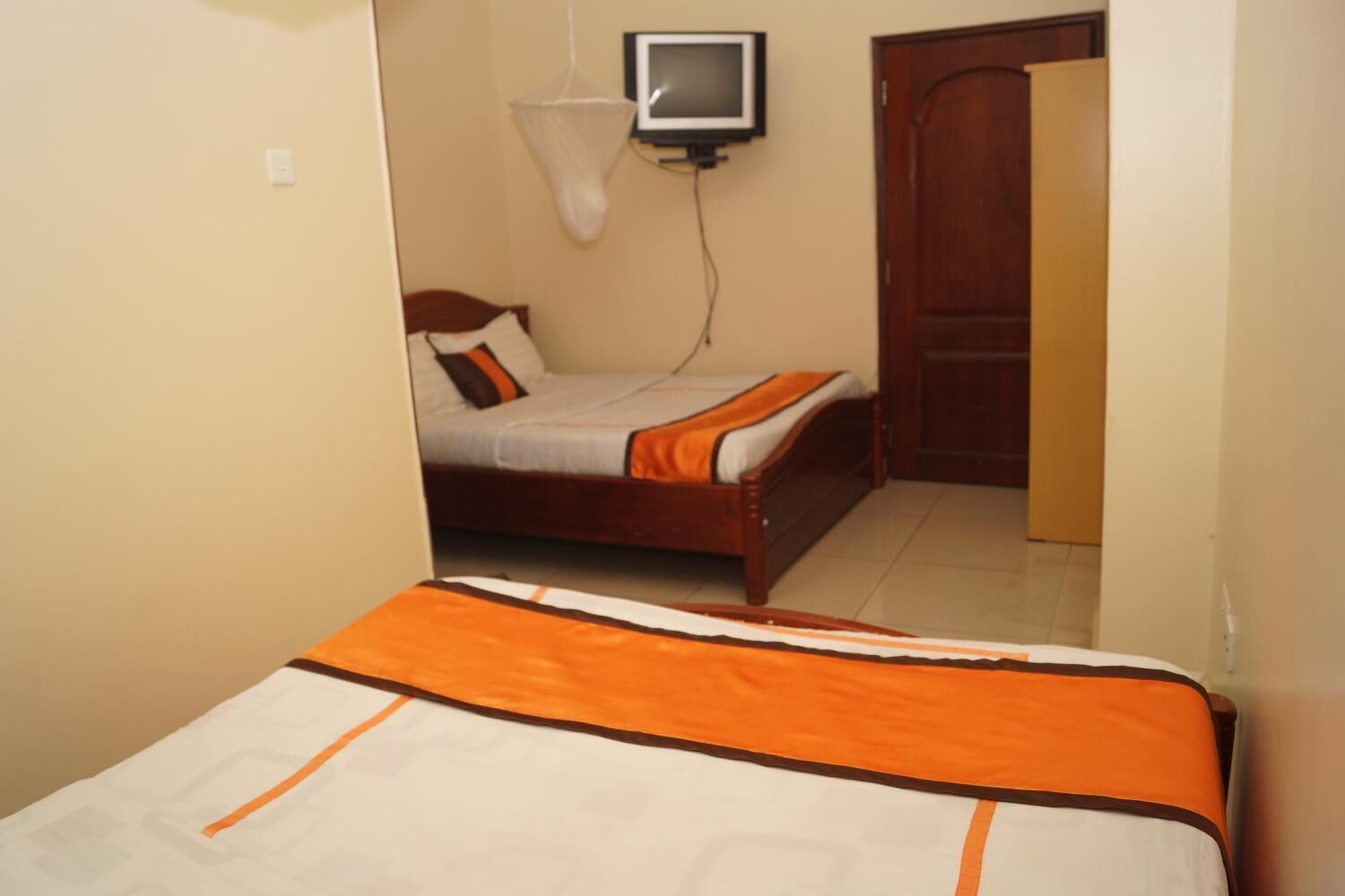 Un dormitorio con cama, televisión montada en la pared y puerta de madera.