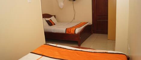 Un dormitorio con cama, televisión montada en la pared y puerta de madera.
