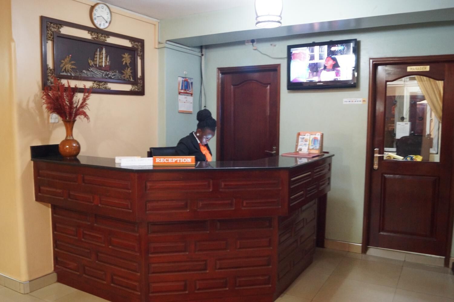 A reception desk with a clock, a television, and a door labeled "MANAGER".