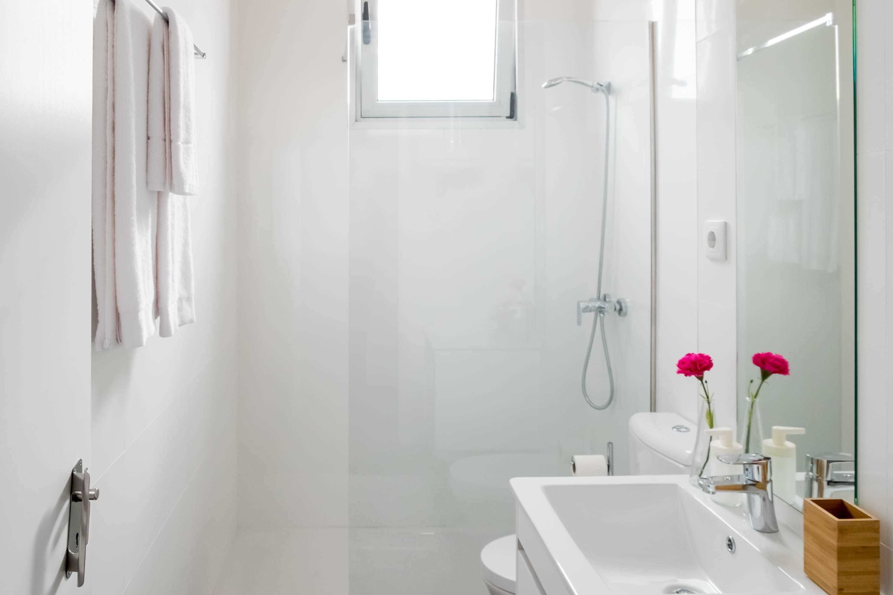 A modern bathroom with a glass shower enclosure, a white sink with a mirror, and a toilet.