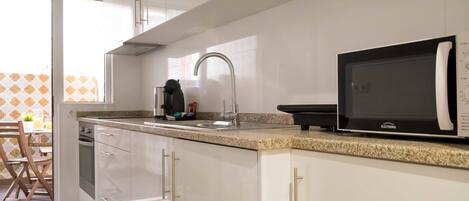 A modern kitchen with white cabinets, a granite countertop, a built-in microwave, and a coffee maker.