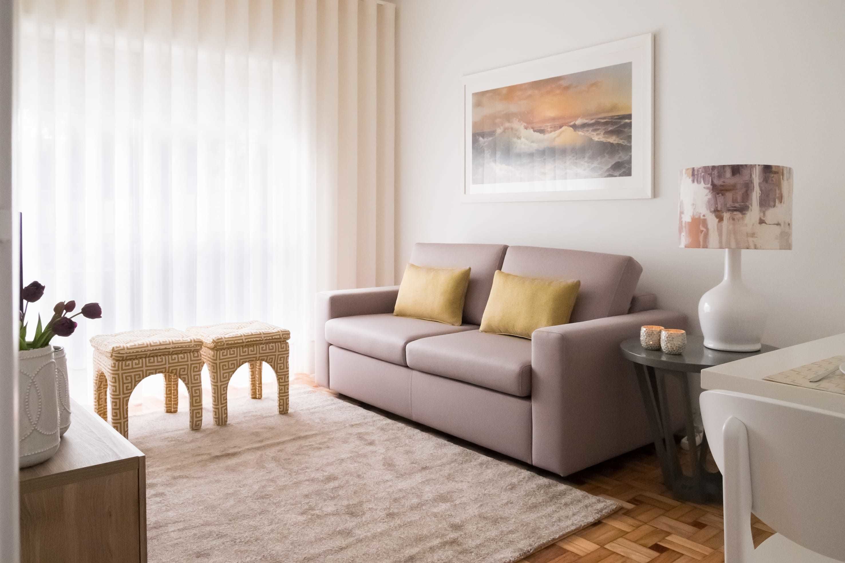A modern living room with a sofa, two small side tables, a lamp, and a framed picture on the wall.