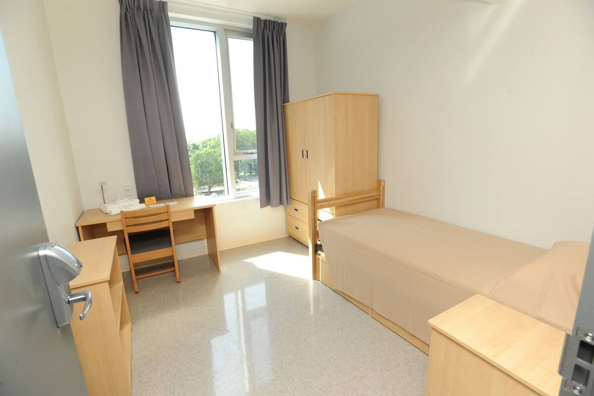 A bedroom with a bed, a desk, a chair, and a wardrobe.