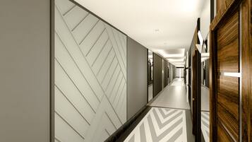 En modern hall med en vägg med geometriskt mönster, en väggpanel i trä och ett golv med sicksackmönster.