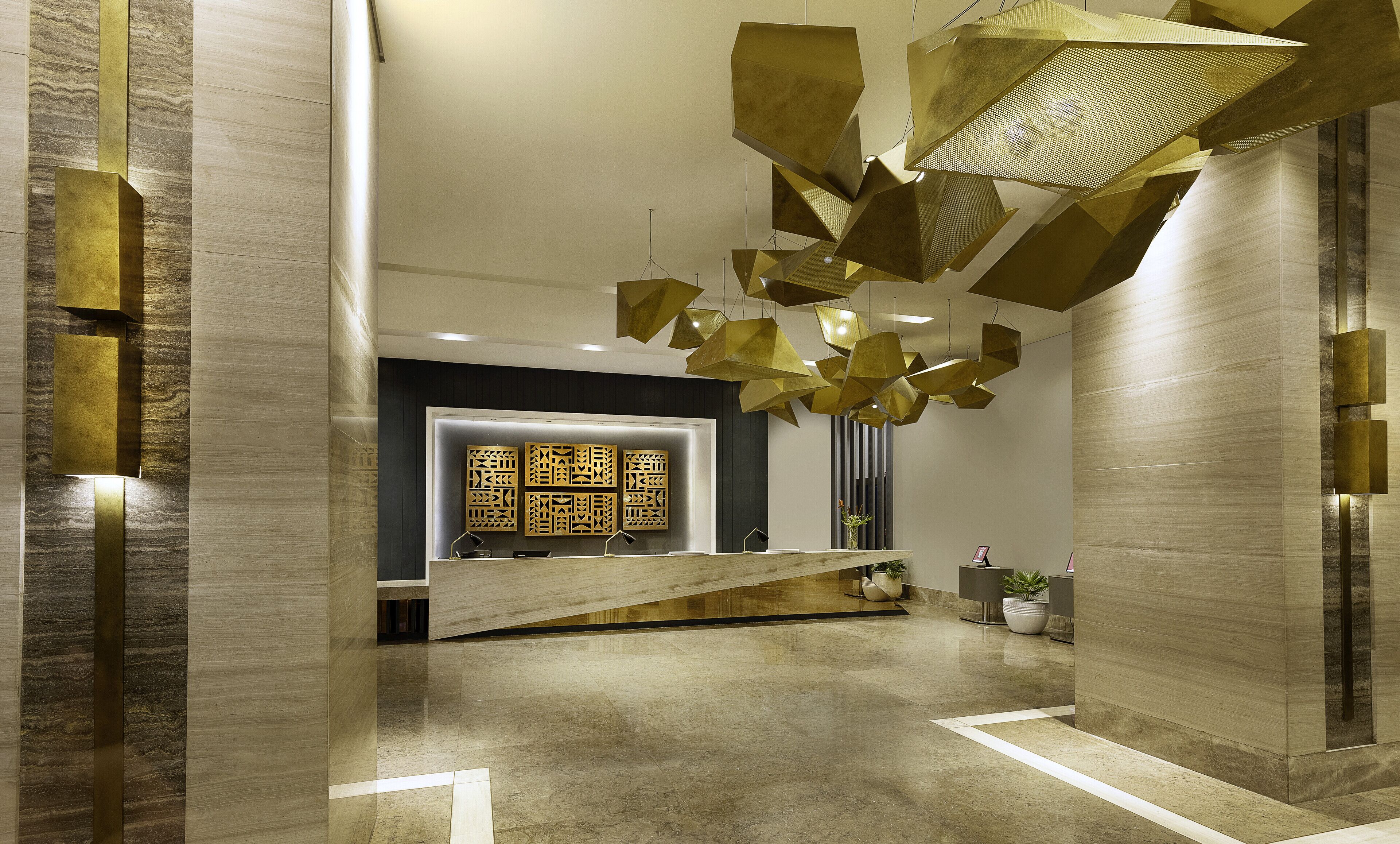 Un espace d’accueil moderne agrémenté d’un luminaire aux formes géométriques, d’un comptoir de réception et d’un panneau décoratif mural.