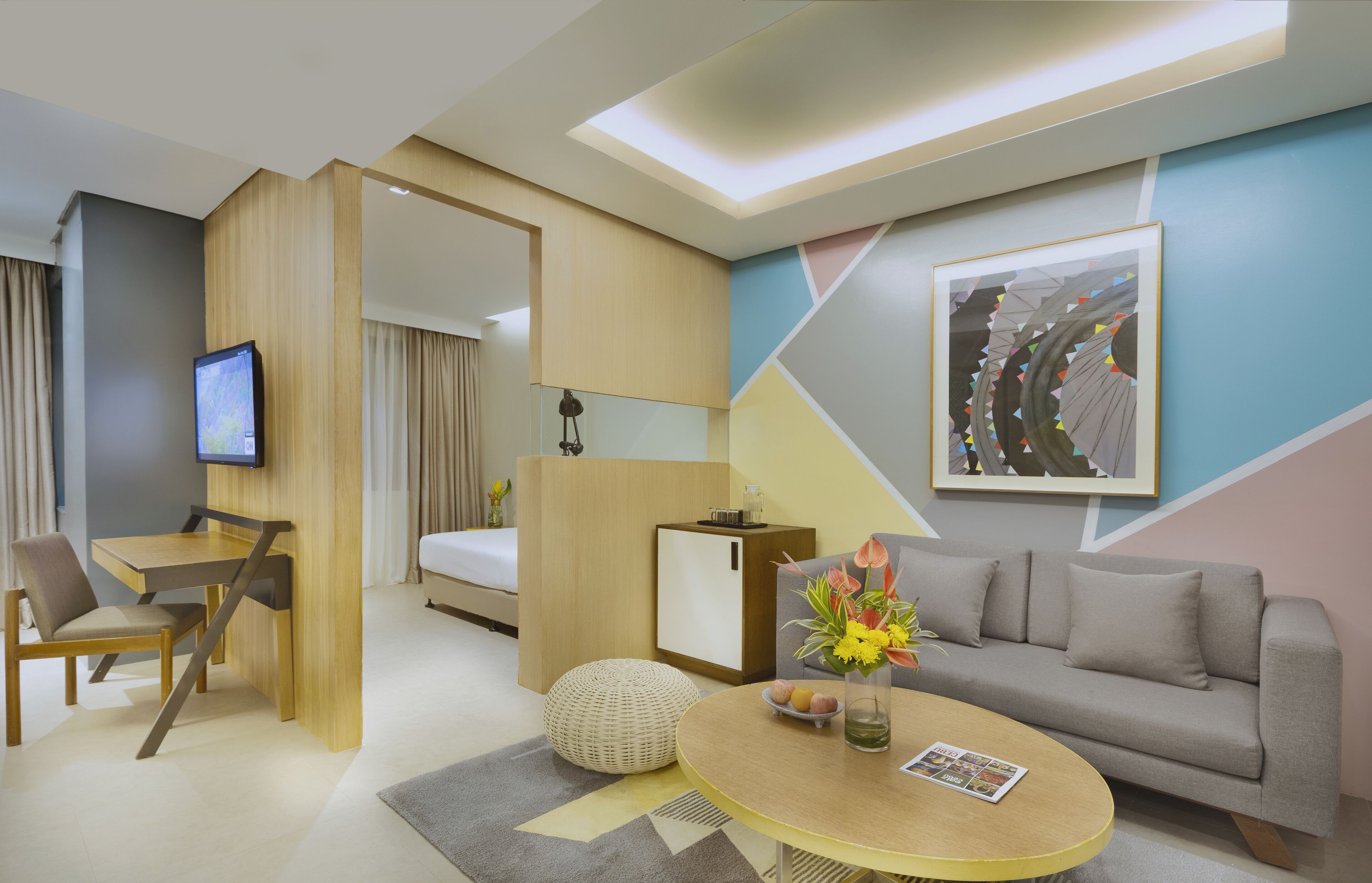 Una moderna camera d'albergo con un letto, una poltrona, un'area pranzo con tavolo, una TV e un elemento decorativo a parete.