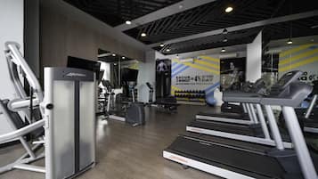 Un gimnasio con cintas de correr, máquinas elípticas y equipo de pesas.