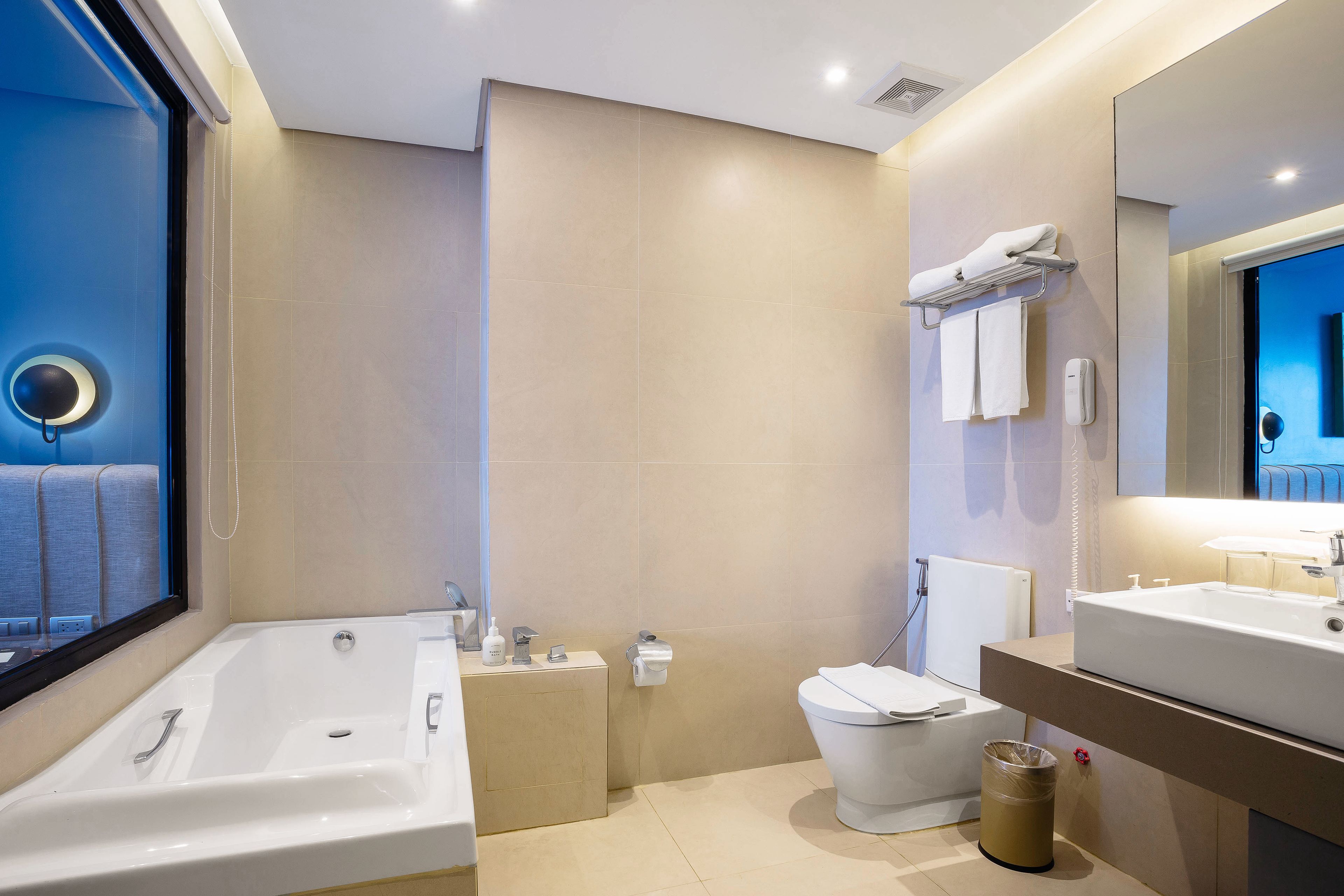 Een moderne badkamer met een bad, toilet en wastafel.