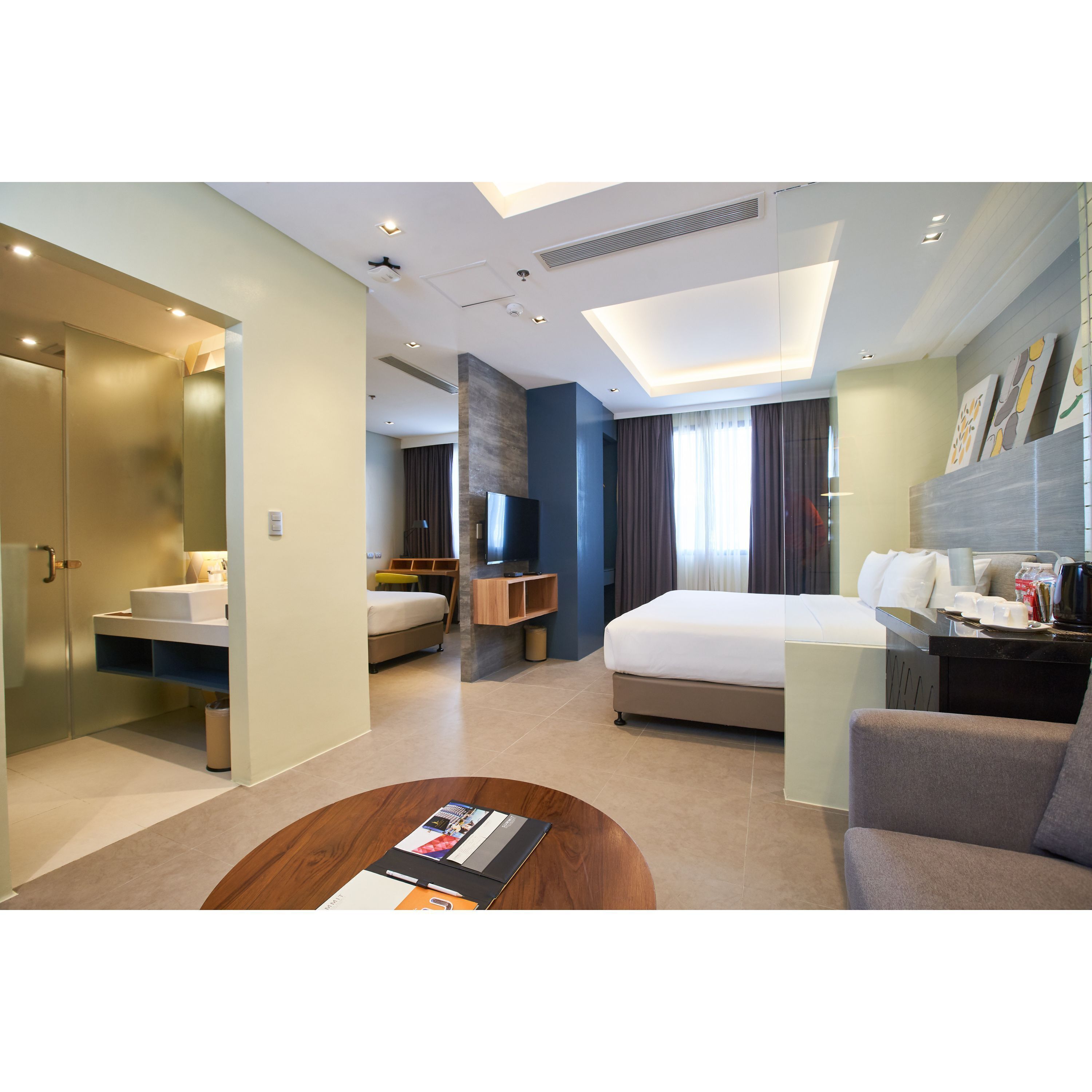 A modern hotel room with a large bed, a desk, a sofa, and a bathroom.