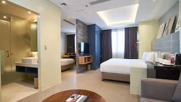 Una habitación de hotel moderna con una cama grande, un escritorio, un sofá y un baño.