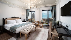 Une chambre à coucher luxueuse, dotée d’un grand lit, d’une banquette, d’un bureau et d’une télévision.