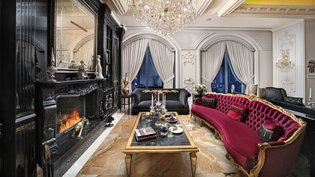Une chambre luxueuse avec une grande cheminée, un confortable canapé rouge et un décor élégant.