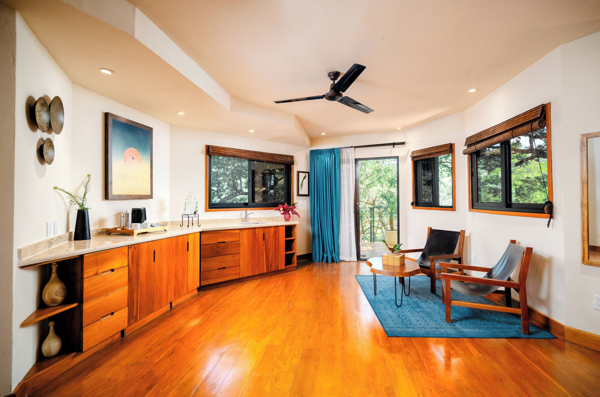 A spacious kitchen with wooden cabinets, a large window, and a ceiling fan.