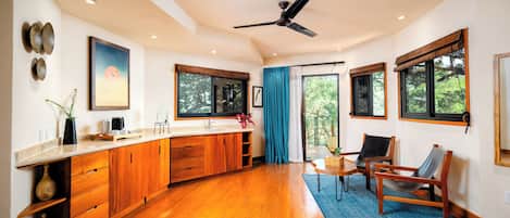 A spacious kitchen with wooden cabinets, a large window, and a ceiling fan.