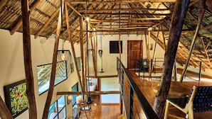 A rustic interior with exposed wooden beams, a high ceiling, and a cozy seating area with a bench and a table. - TreeCasa Hotel & Resort (San Juan del Sur)