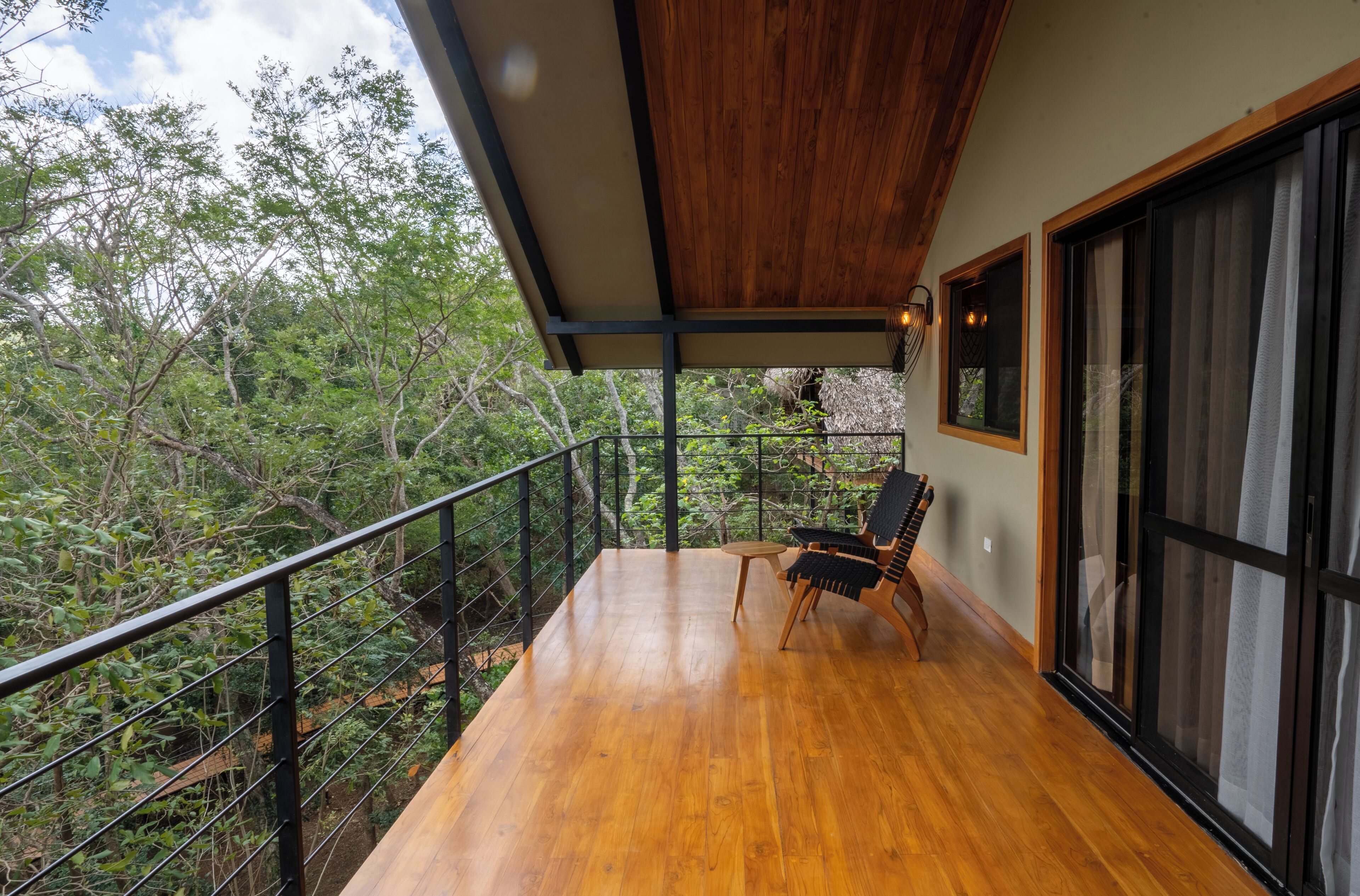 Un balcone con pavimento in legno, una sedia e un tavolo.