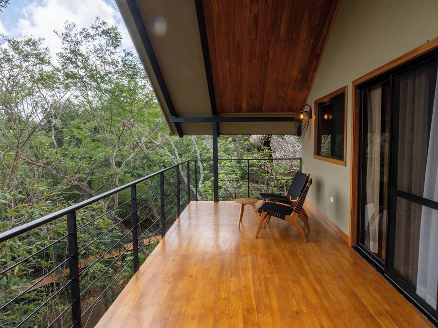 A balcony with a wooden floor, a chair, and a table.