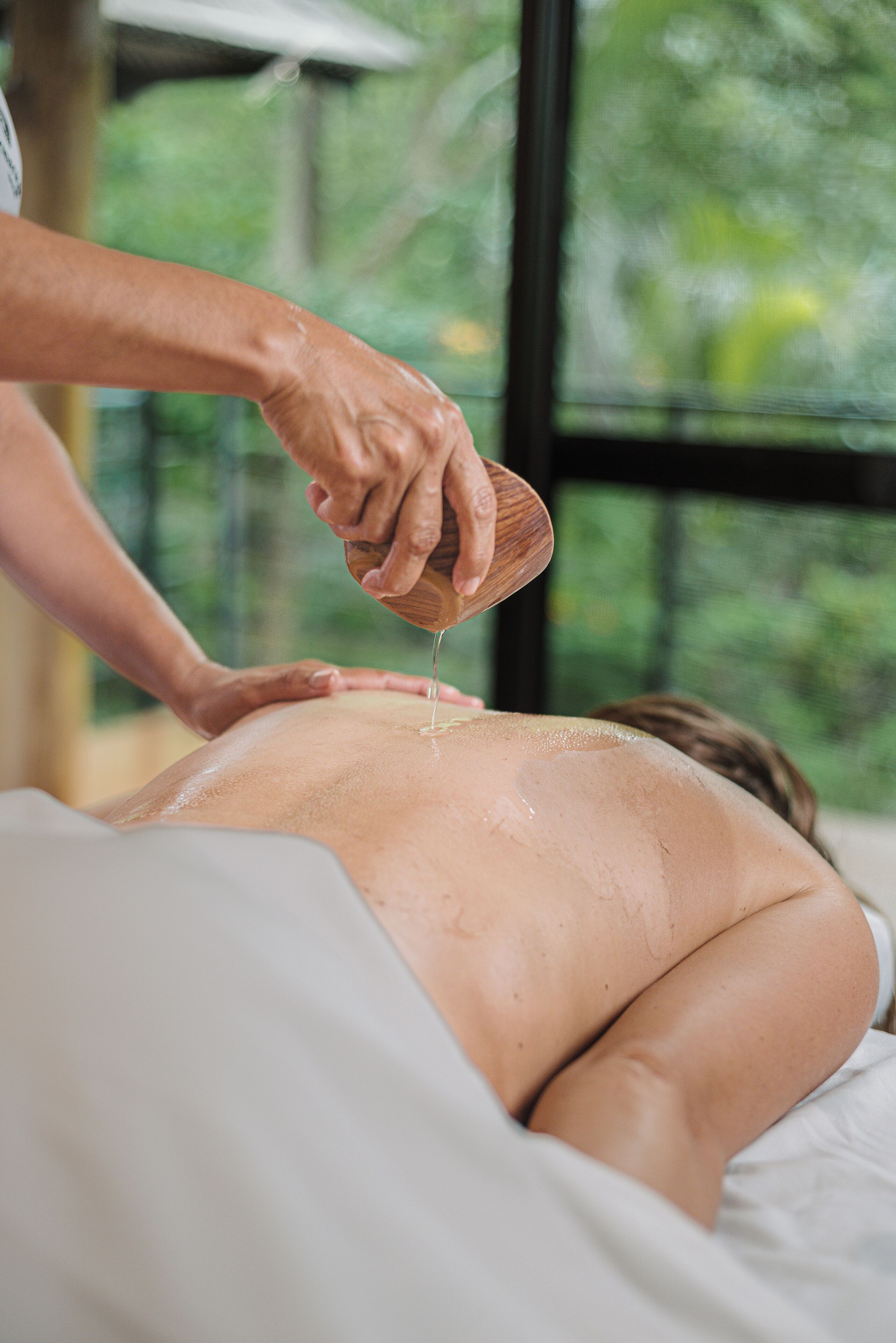 A person receiving a back massage with a wooden tool.